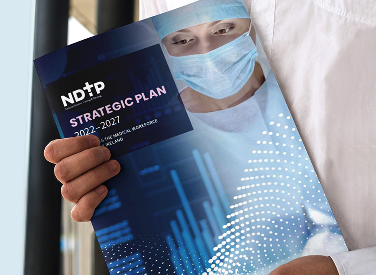 Man holding a report showing the cover with an image of a surgeon wearing a mask