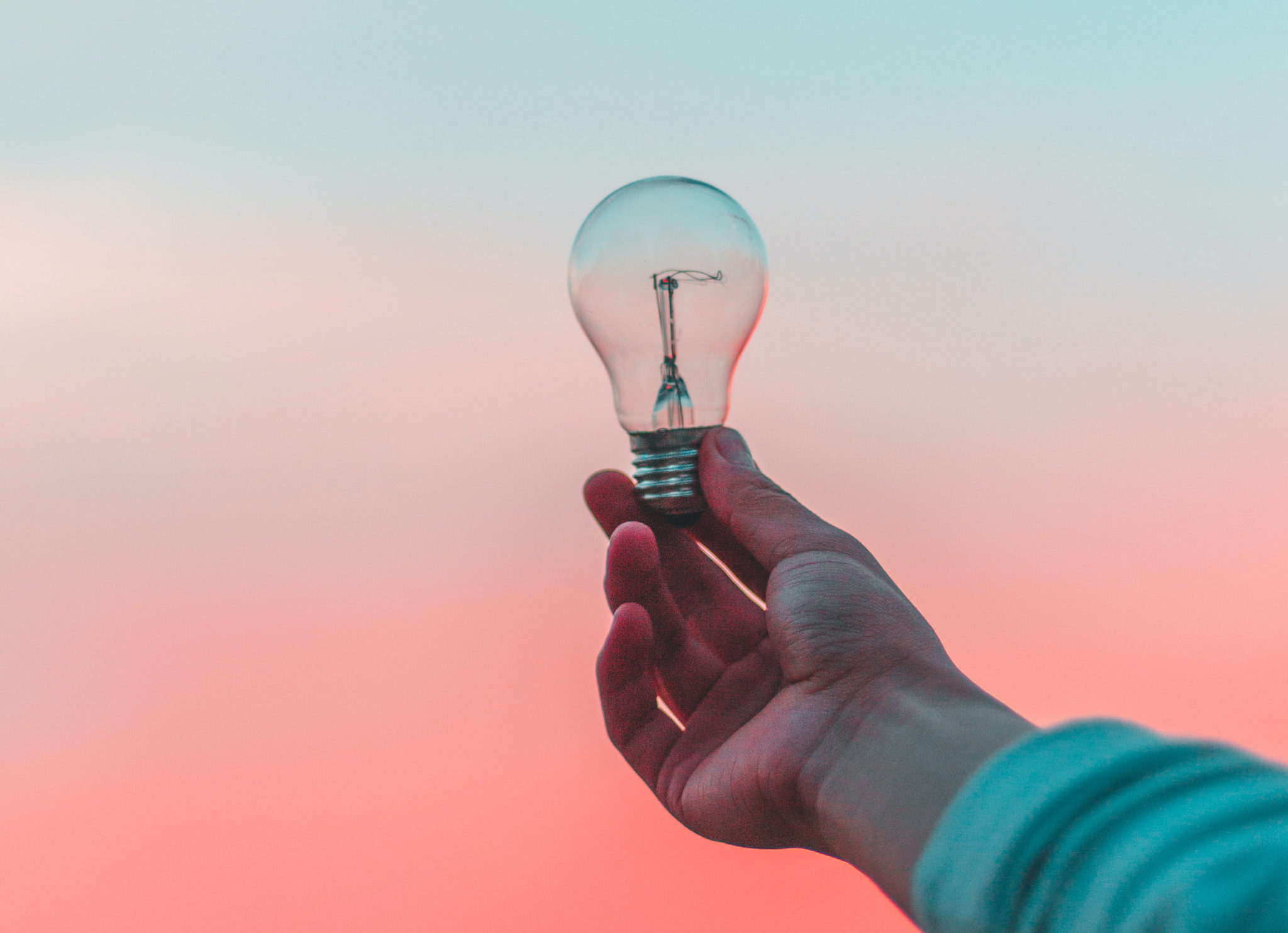 Man holding a lightbulb against a pink backdrop